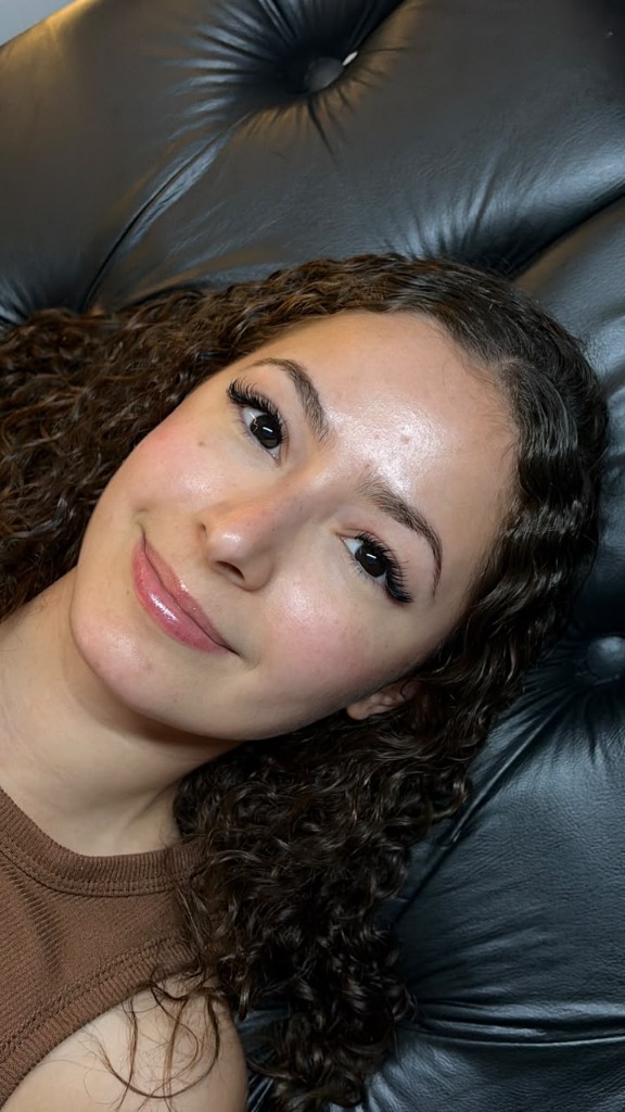 Extensão de cílios em cliente de cabelo cacheado e sorriso suave